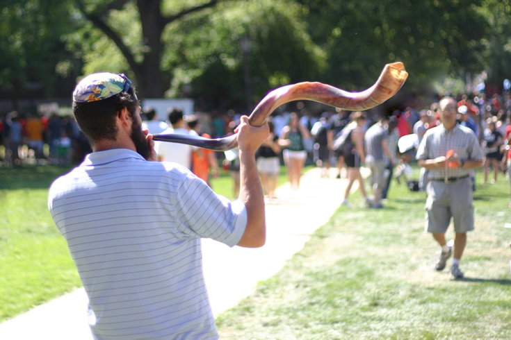 A man blows a shofar in a field