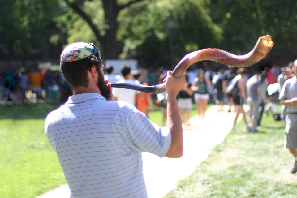 A rabbi outdoors holding a shofar