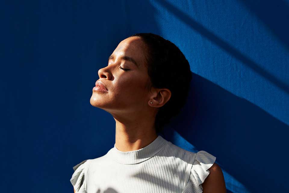 a woman lifts head back in sunlight