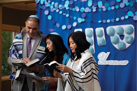 A child is bat mitzvahed with her parents. 