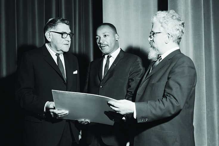 George Maislen (left), president of the United Synagogue of America, presents an award to Martin Luther King Jr. (center), "for translating the prophetic vision of Abraham Lincoln into a living reality" in November 1963. Heschel looks on on the right.