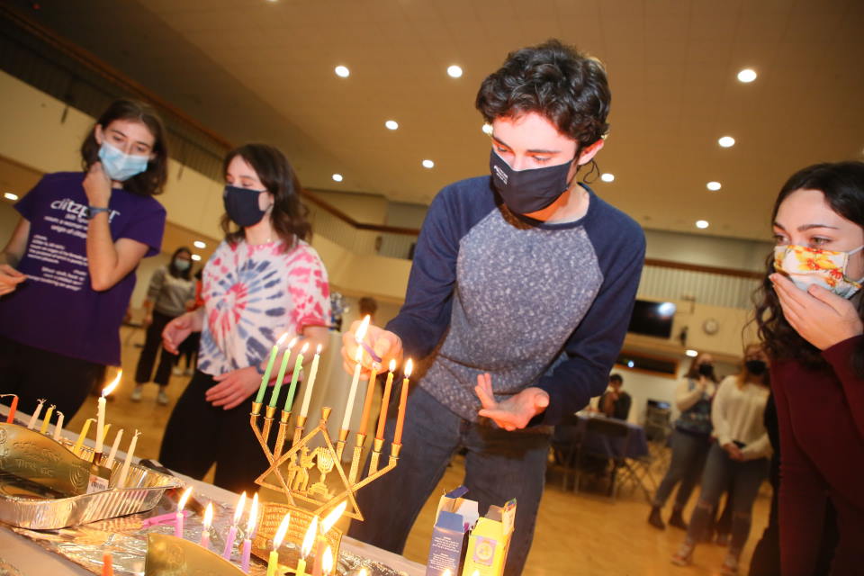 A student lights a menorah at a Hanukkah celebration. 