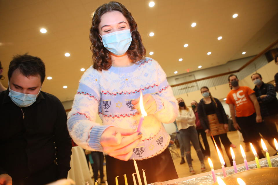 Student lighting Hanukkah candles