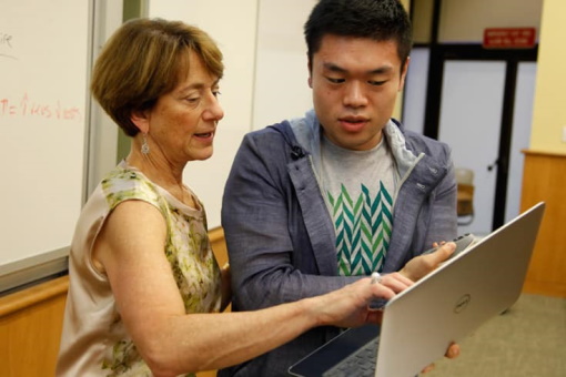 Student and teacher looking at laptop