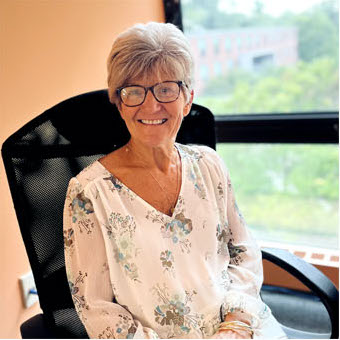 Cheryl Sweeney, academic administrator, sits in the Journalism Program office.