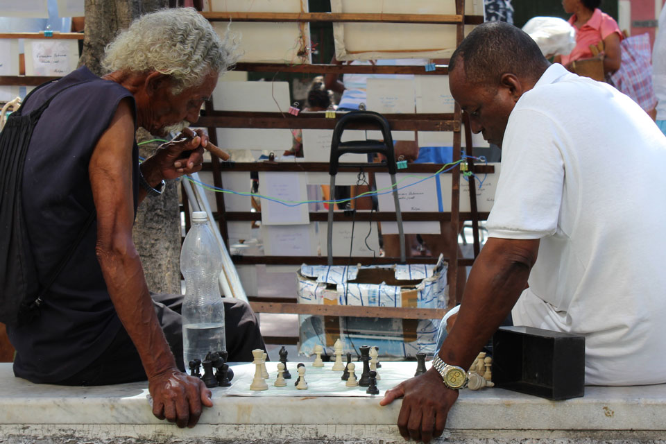 Two men playing chess, one of whom is smoking a cigar.