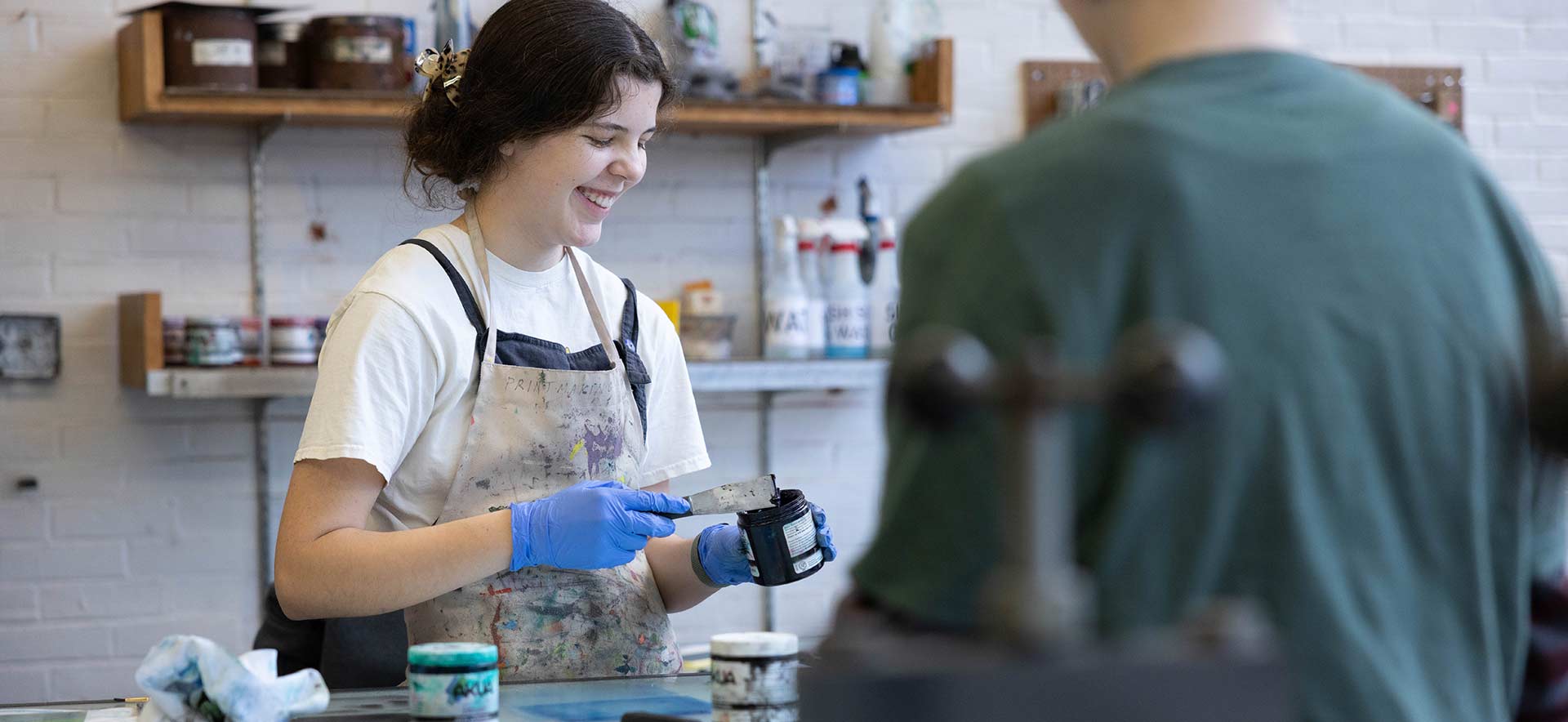 A student spreads some ink in a printmaking class while working on a monotype