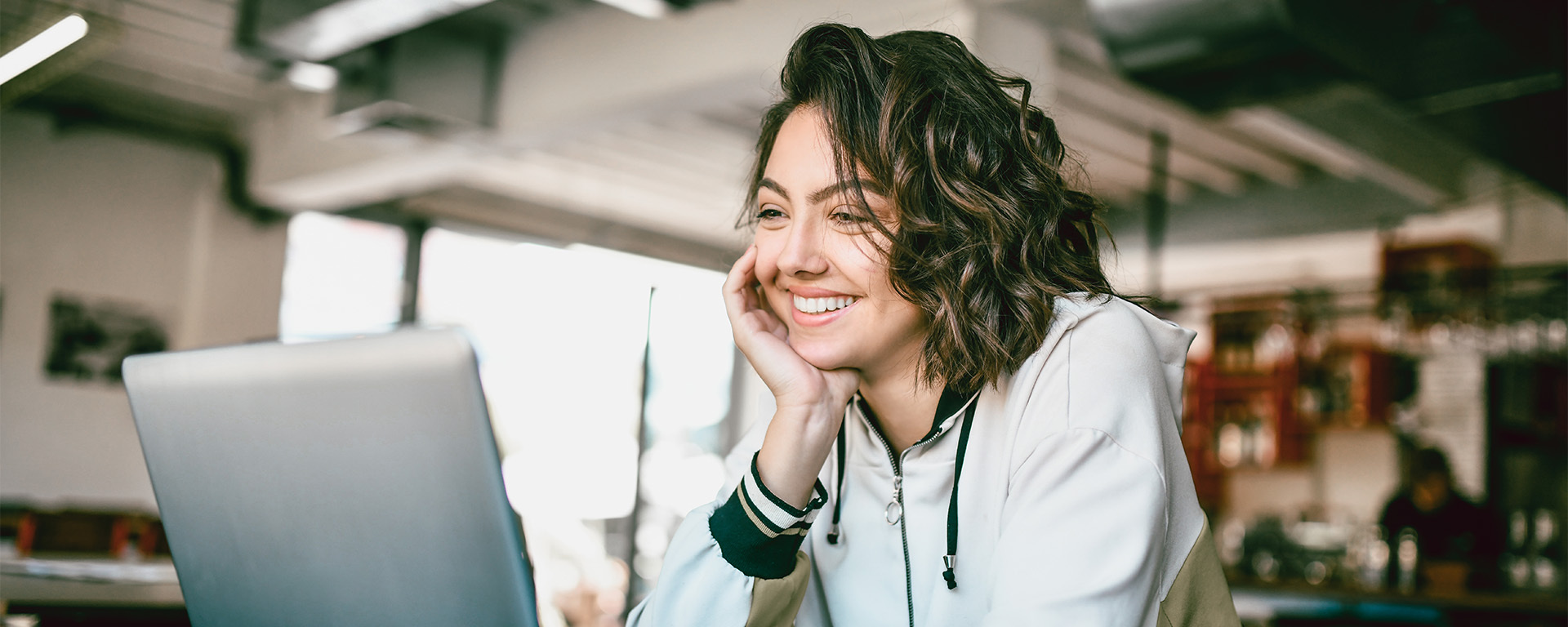 A woman smiles while looking at a laptop screen