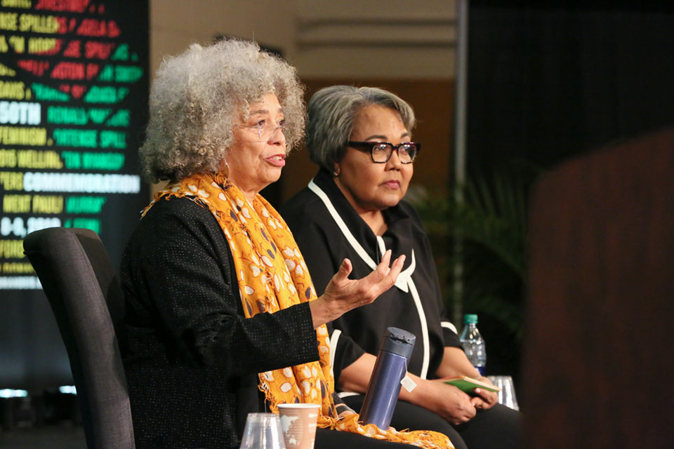 Angela Davis sits with Julieanna Richardson on a stage in front of the AAAS 50th Anniversary Banner