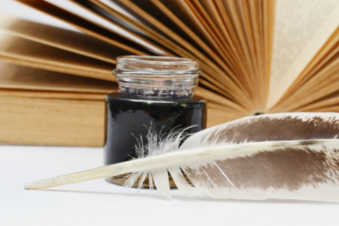 A quill and ink next to a book