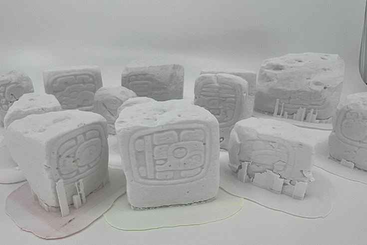 a collection of small white blocks with mayan artwork, created on a 3D printer