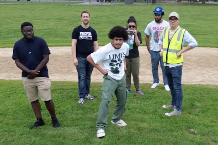 Six people stand in a ballpark.