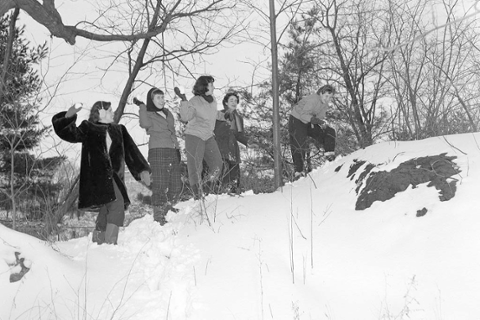 a smiling group of students prepare to throw snowballs on a hill