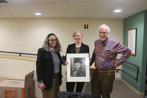 Three people in a semi circle around a photo of a young boy