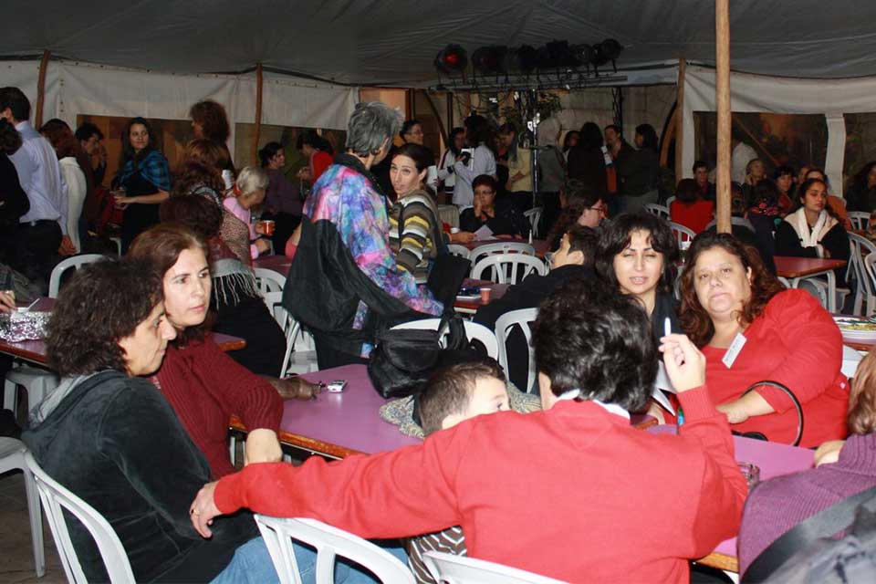 Crowd of people sitting and standing around tables in a tent