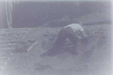Black and white photo of person digging in dirt on a hill