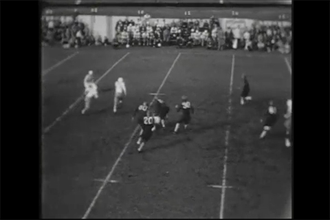 Black and white archival footage of a football game