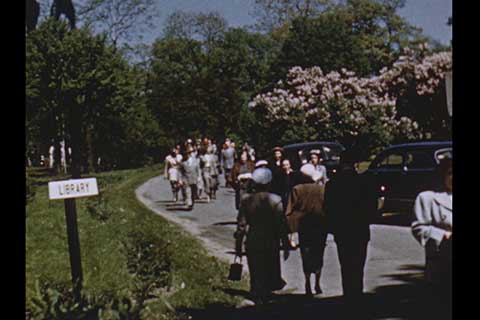 Well-dressed crowd walking down the street to an event on a summer day