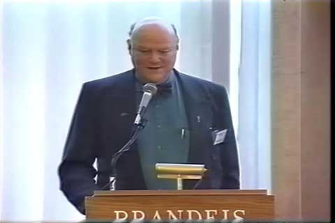 Man in suit standing at a podium and speaking into a microphone