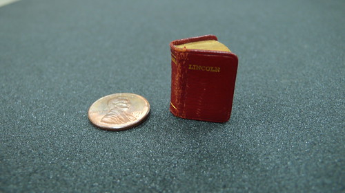 A book the size of a coin placed next to a coin