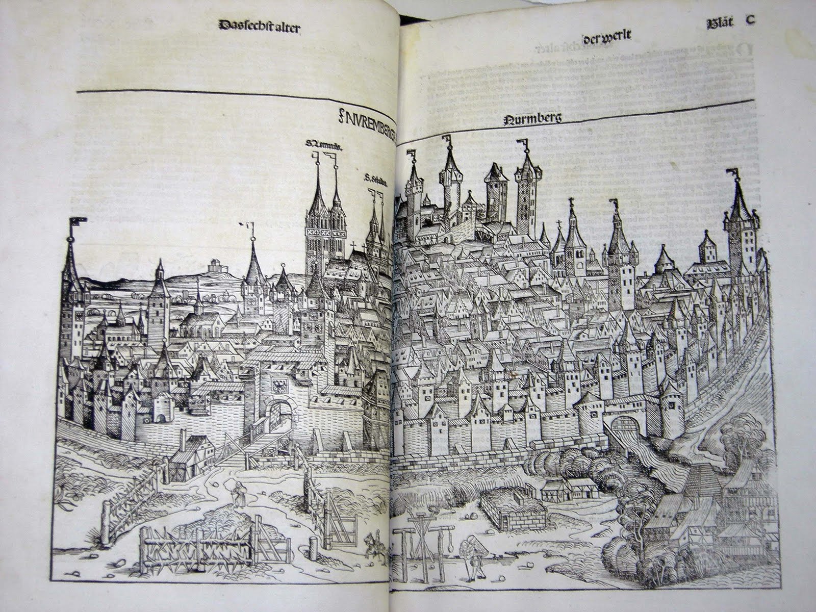 The german edition of The Nuremberg Chronicles opened to two pages displaying a woodcut illustration of the walled city of Nuremberg