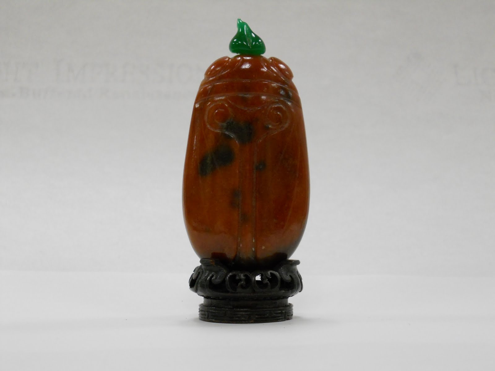 Chinese snuff bottle in the shape of a cicada with an amber body and an assymetrical jade green cap