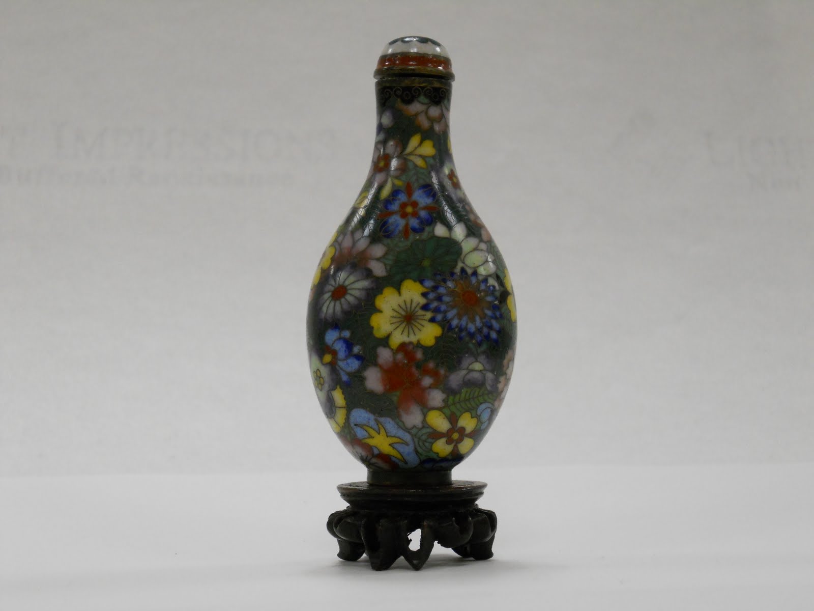 Chinese snuff bottle with colorful flower designs atop a green background