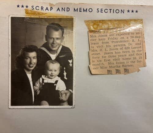A page of a scrapbook with a black and white photo of a man, woman, and young child, and a newspaper clipping announcing their travel to visit family.