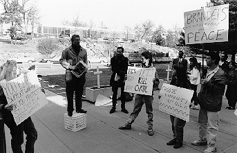 Students holding signs at the Student Peace Demonstration at Usdan November 1990. Behind them are crosses in white boxes filled with soil.
