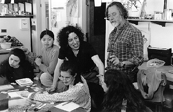 Bob Lange and Robin Dash co-teaching science and art class 1997. Four students are working on a project at a table with the teachers standing behind them and engaging with them.