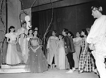 Large group of student actors in costume on stage during a theater production.