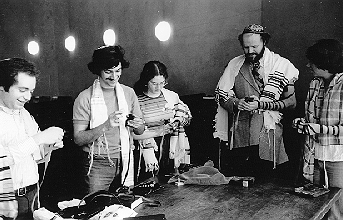 Minyan — Four women and one man wearing prayer shawls standing around a table.