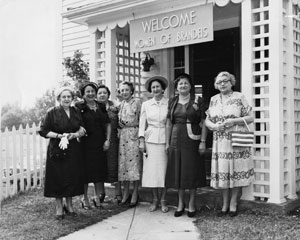Photo of 7 women standing at the entrance of a building with the sign above them that says: Welcome Women of Brandeis.