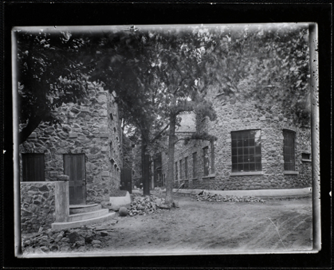 View of the castle through the trees, with the dirt pathways surrounding the building.