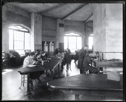 Lab in the castle with students busy at numerous workstations.  Some are wearing lab coats.