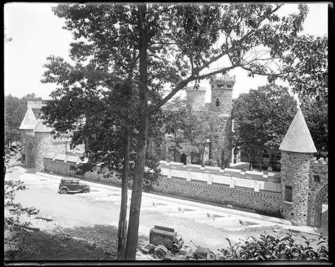 View of the Castle with stone wall and arched entranceways. A car is parked by the wall.