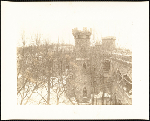 Upper view of castle with snow through bare trees. This photo is faded.