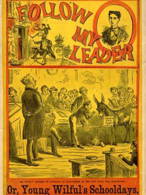 Cover of book "Follow My Leader, Or, Young Wilful's Schooldays." with a picture of a schoolmater standing with a stick behind his back and a group of students surrounding a donkey.