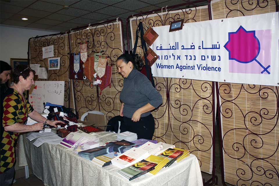 Several women standing by a presentation table at the Women Against Violence conference