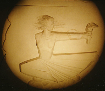Relief in Nathan Seifer Auditorium. Sculptural image shows a woman with arm extended holding a torch.