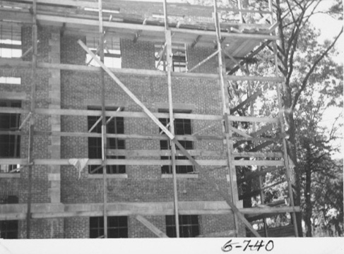 View of the 3rd floor being added to the building, with scaffolding, and trees alongside the building.