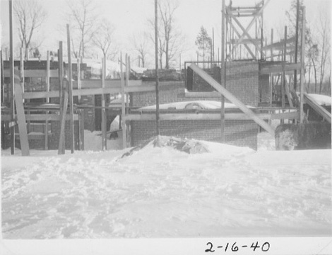 Building under construction, with scaffolding extending up to where the second floor will be.  Snow covers the ground.