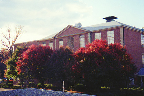 Color photo of Ford Hall as seen from the Administration Building during the fall.  The leaves are a deep scarlet color.