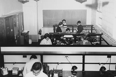 Aerial view of a science lab in Sydeman Hall in 1954. In this picture 9 students can be seen working on projects.