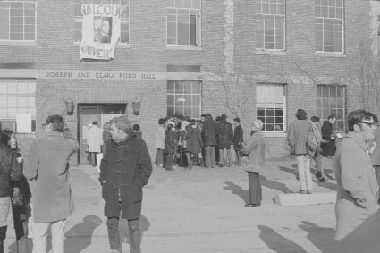 Students gathering outside Ford Hall. The banner hanging on wall of Ford Hall reads "Malcolm X University." January 8-18, 1969