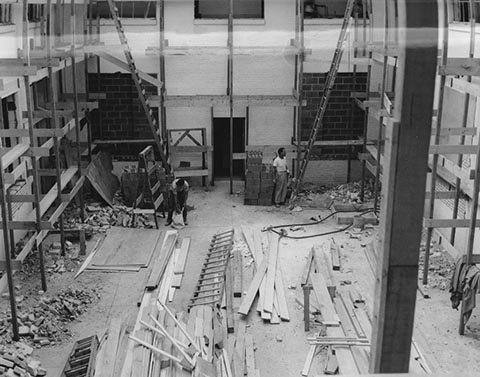 Nathan Seifer Auditorium Under Construction with ladders, scaffolding, piles of lumber and 2 workers.