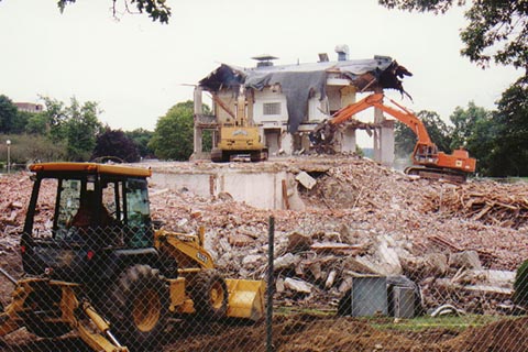 The last remaning corner — Excavators and a tractor are working on the other side of a chain link fence.
