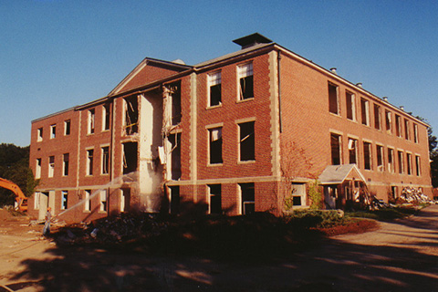 Front of the building after wrecking crew tore down the central section. A hose is spraying the building.