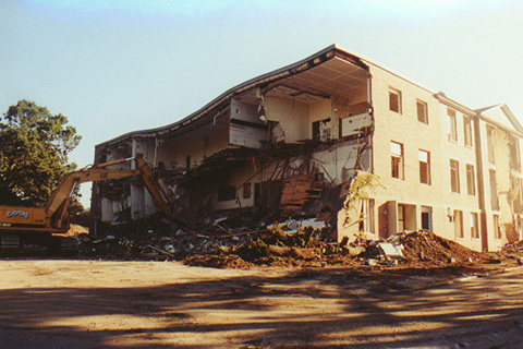 Sydeman Wall facing  former Parking Lot F is shown here with the entire facade gone, the roof caving in and the rooms inside visible. In front is a pile of rubble