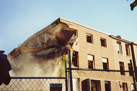 Second in a sequence of an excavator tearing down a corner of Sydeman Hall 